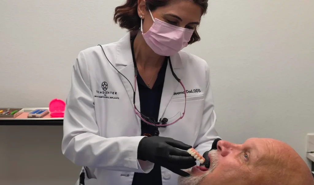 Oral surgeon evaluating a full arch dental implant prosthesis with a patient during treatment planning consultation