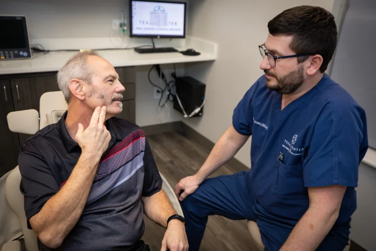 Dr. Aaron Vickers, oral surgeon at Texas Center for Oral Surgery & Dental Implants, consulting with a patient about dental implants during an in-office visit.