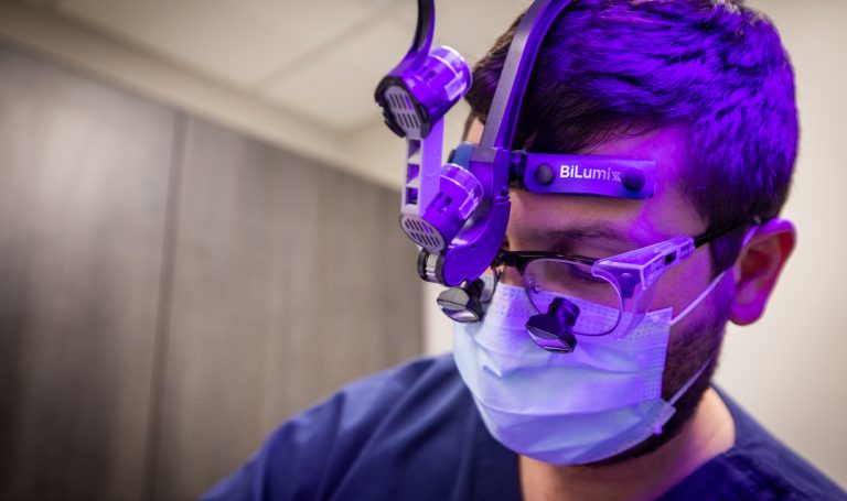 Dr. Vickers wears surgical loupes and a mask while focused on a procedure, the kind of precision instrumentation that complex implant cases demand.