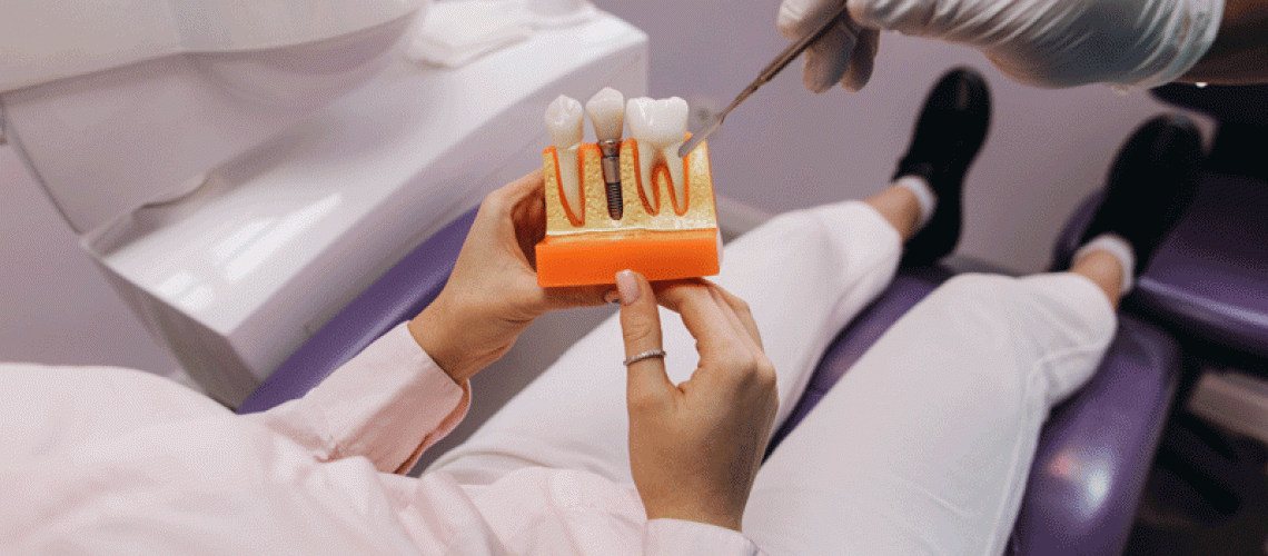 Patient in chair holding a dental implant model with thew doctor giving information