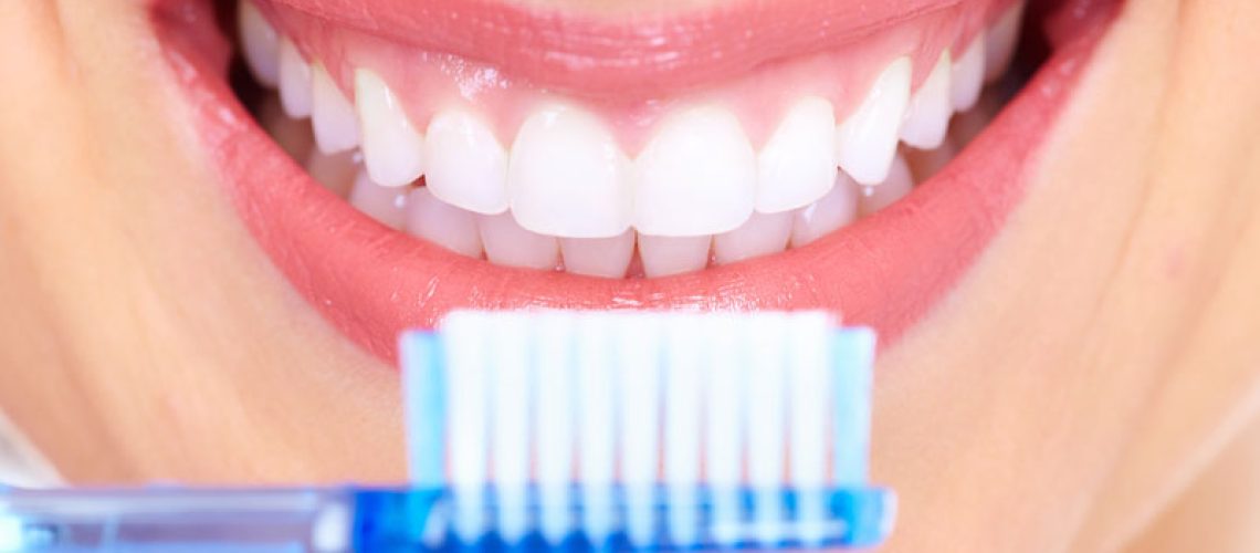a full mouth dental implant patient smiling with a toothbrush.
